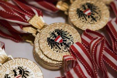 Goldene Medaillen mit blauen und roten Bändern, die das Wappen Österreichs zeigen.