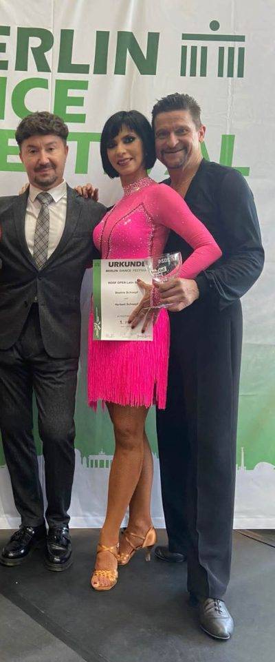 Drei Tänzer posieren stolz mit einer Urkunde und einem Pokal nach dem Berlin Dance Festival.