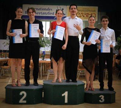 Siegerpaare eines Tanzwettbewerbs stehen stolz auf dem Podium und halten ihre Urkunden in der Hand.