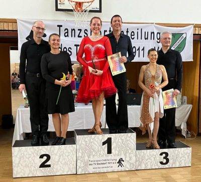 Eine Gruppe von Tänzern steht stolz auf einem Siegertreppchen während einer Tanzveranstaltung.