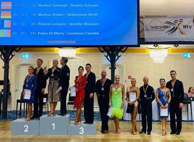 Eine Tanzsport-Wettbewerbsveranstaltung mit mehreren Paaren auf dem Siegertreppchen und Medaillenverleihung.